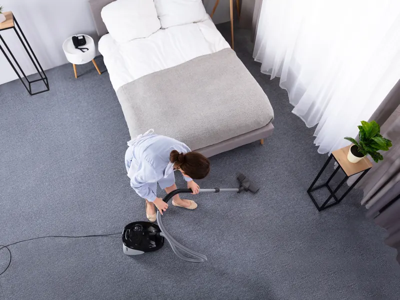 Vacuuming a bedroom with the bed made during a home clean in Perth